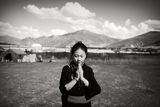 01 一位來自玉樹游牧地帶的藏族女子，雙手合十做出祈福手勢